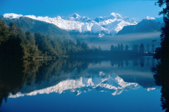 Snow covered mountains reflected in a calm lake.